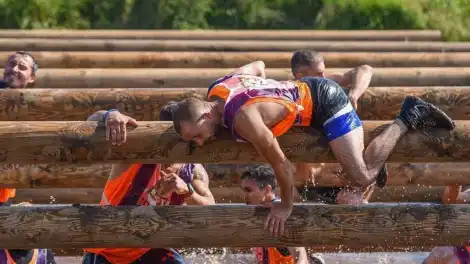 спортсмен лезет по бревну