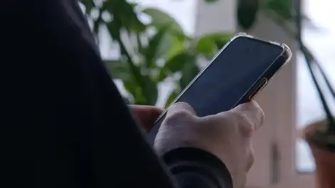 человек держит в руках телефон смотрит в экран смартфона