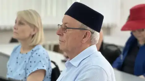 мужчина в тюбетейке сидит слушает спикера