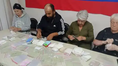 компания людей сидит за столом и упаковывает комплекты сухого душа