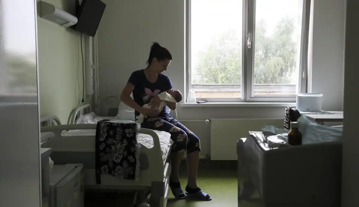 Женщина в роддоме с новорожденным на руках