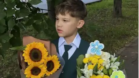 мальчик школьник держит в руках цветочный букет