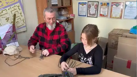 девочка учит деда плести браслеты выживания