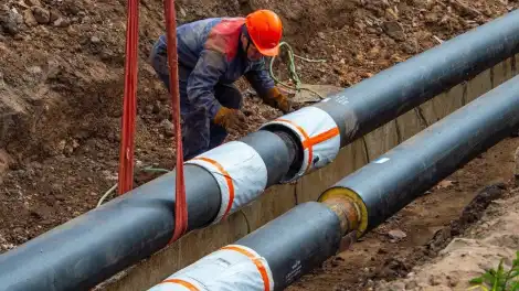 В траншею опускают новую трубу водоснабжения