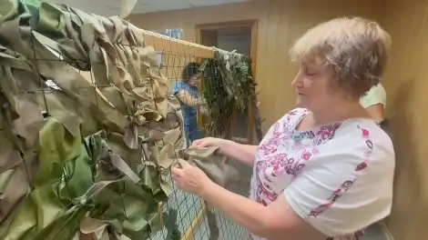 женщина плетёт маскировочную сеть