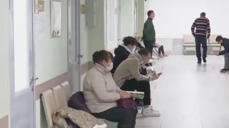 люди сидят в коридоре больницы и ждут своей очереди