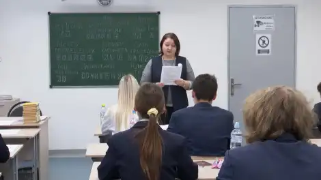 учитель стоит перед учениками в классе