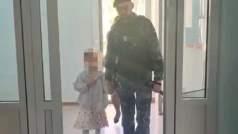 сотрудник полиции ведет девочку за руку