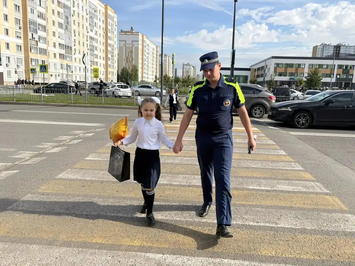 инспектор ГАИ ведёт за руку школьницу чеез пешеходный переход