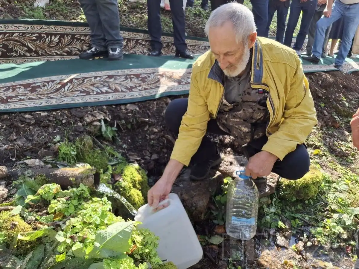 мужчина набирает воду из родника