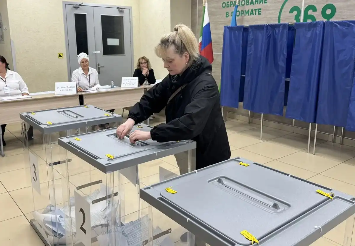 женщина кидает бюллетени в урну