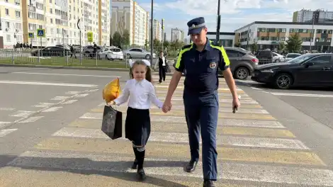 инспектор ГАИ ведёт за руку школьницу чеез пешеходный переход