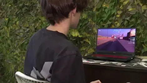 юноша сидит за компьютером и играет в игру
