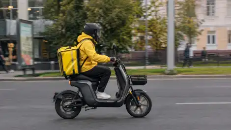курьер на мопеде едет по городу