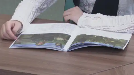 Ученица сидит за партой в школе с книгой