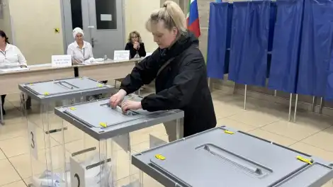 женщина кидает бюллетени в урну