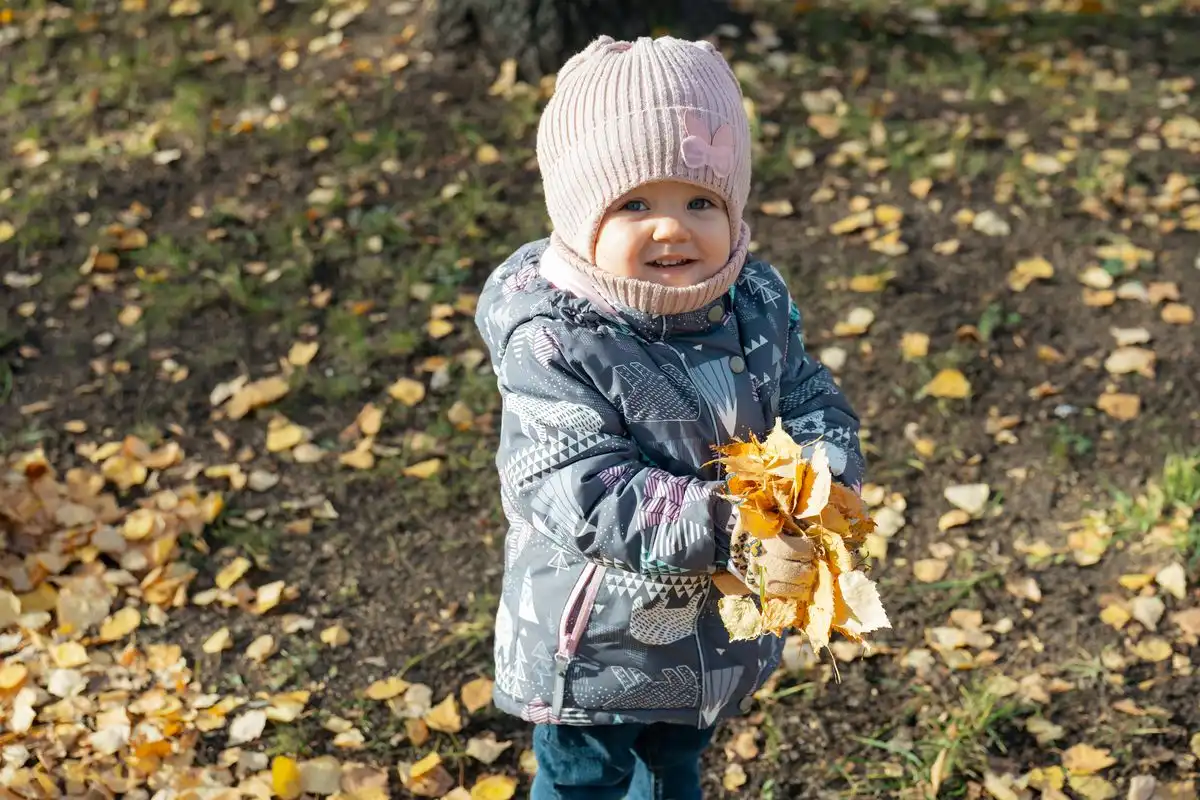 маленькая девочка держит в руках листья