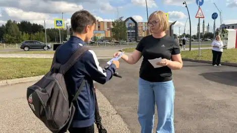 Женщина вручает подростку листовку о вреде наркотиков