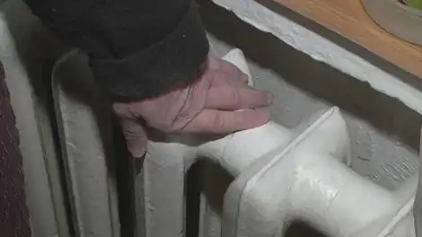рука трогает батарею