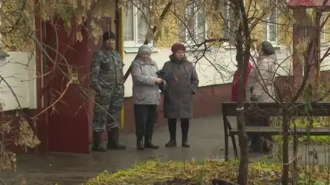 пенсионеры стоят и общаются у подъезда
