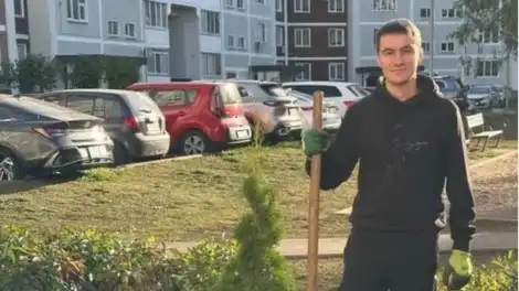 молодой мужчина ухаживает за цветником во дворе в Нижнекамске