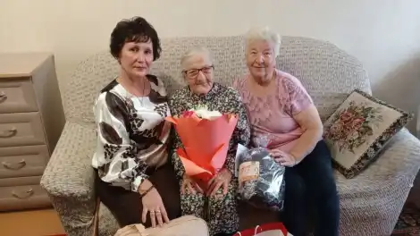 98-летняя нижнекамска Анастасия Грызунова сидит в свой день рождения с гостями и с букетом цветов